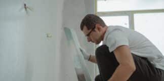 How Can You Minimize Disruptions During a Commercial Painting Project? A man in white shirt painting a house