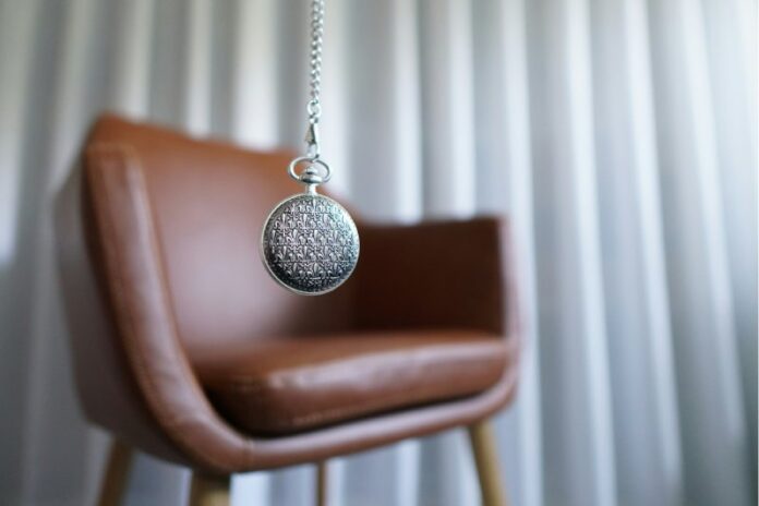 Silver round pendant on brown wooden chair
