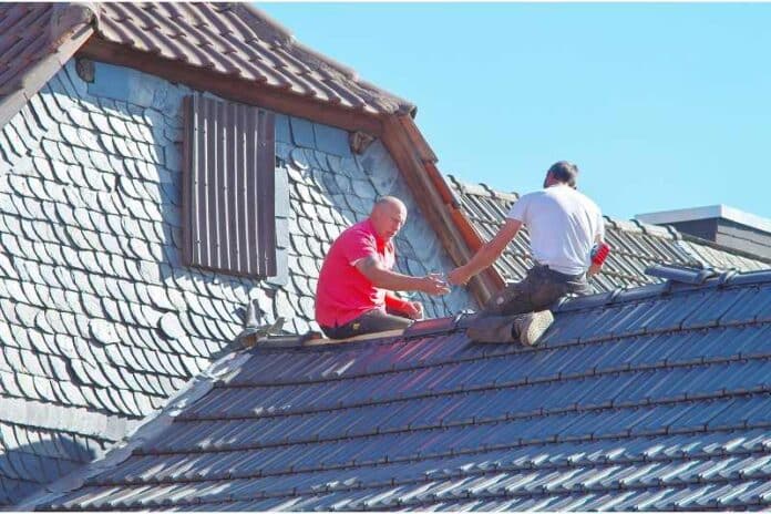 Two men working on the roof of a house